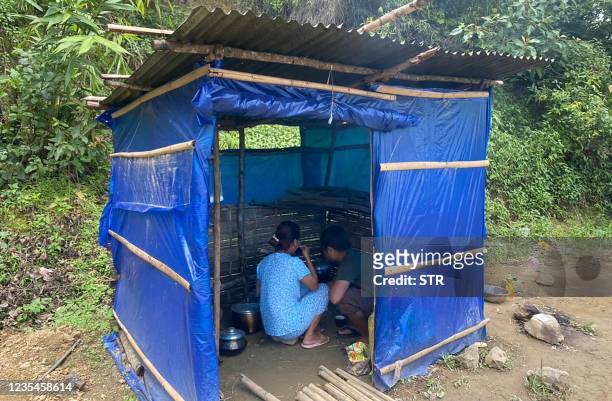 Refugees cook food in a basic shelter at Farkawn quarantine camp in India's eastern state of Mizoram near the Myanmar border on September 24 after...