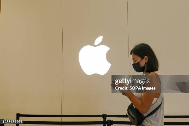 Woman walks past an Apple logo on the building of the A13 Apple store in Taipei after the launch of the new iPhone 13 series phones.