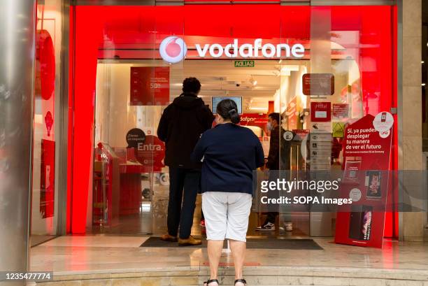 People are seen at the door of the Vodafone mobile store in Valencia.