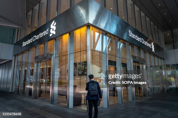 Man stands in front of the Standard Chartered building while talking on the phone.