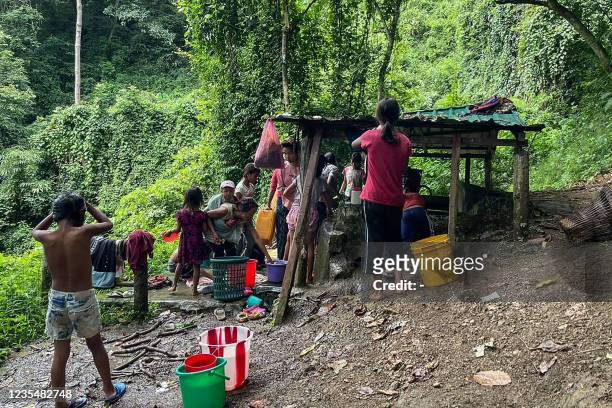 This picture taken on September 24, 2021 shows refugees collecting water at Pang village in India's eastern state of Mizoram near the Myanmar border,...