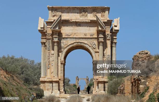 People walk under the Arch of Sptimus Severus in the ancient Roman city of Leptis Magna near the coastal Libyan city of Al-Khums, 120Km east of the...