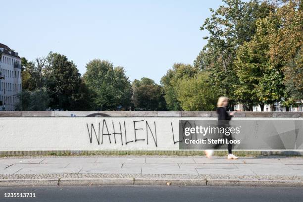 Woman walks past a grafitti that says "Wahlen LOL" on the day of federal parliamentary elections on September 26, 2021 in Berlin, Germany. Voters are...