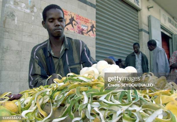 Un vendeur de fruits pèle des oranges sur sa brouette en attendant les clients, le 23 Février 2001 à l'angle d'une rue du centre ville de Dakar. Les...