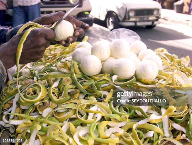 Un vendeur de fruits pèle une orange sur sa brouette en attendant les clients, le 23 Février 2001 à l'angle d'une rue du centre ville de Dakar. Les...