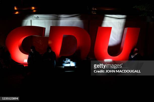 Journalists sit next to a CDU logo outside the Christian Democratic Union headquarters after the German general elections in Berlin on September 26,...