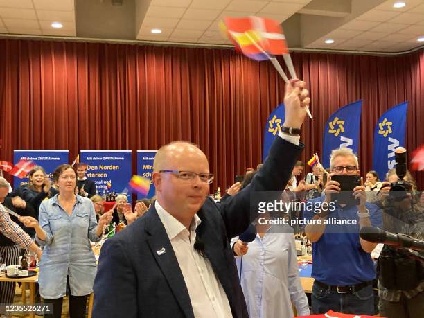 September 2021, Schleswig-Holstein, Flensburg: Stefan Seidler, top candidate of the Southern Schleswig Voters' Association waves flags with the...