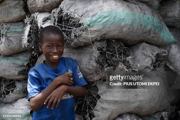 Vendor lean on piles of 15kg bags of charcoal displaced for sale along the road, which many people use for cooking but has become scarce following...