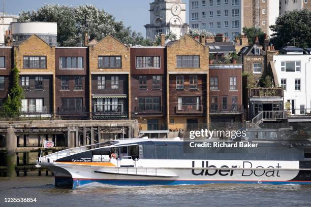Uber Boat's 'Cyclone Clipper' passes Thames riverside residential properties and The Grapes' Pub at Limehouse, on 16th September 2021, in London,...