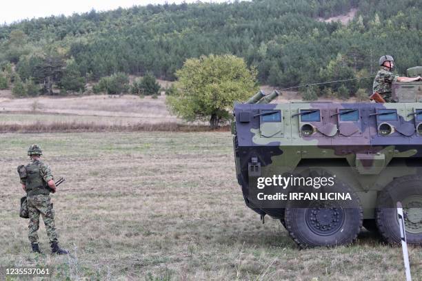Serbian army soldiers stand guard by their armoured vehicle in the village of Rudnica near the southern Serbian town of Raska on September 27 where...