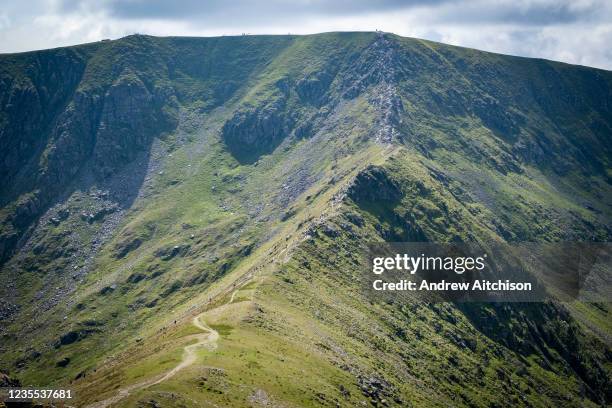 Walkers making their way along Swirral Edge between Helvellyn and Catstye Cam. The Lake District, Cumbria, United Kingdom on the 2nd of August 2021.