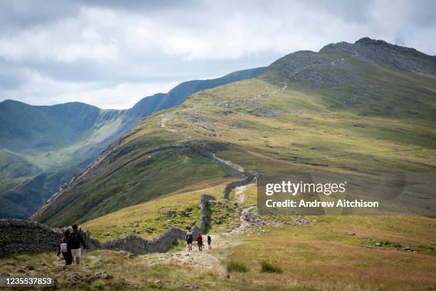 Walkers make their way past hole in the wall up towards striding edge towards Helvellyn Mountain, Lake District, Cumbria, United Kingdom on the 2nd...