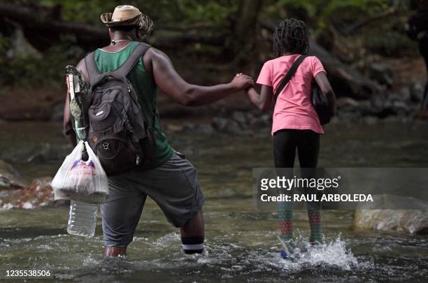 Haitian migrant man holds a girl's hand as they cross the jungle of the Darien Gap, near Acandi, Choco department, Colombia, heading to Panama, on...