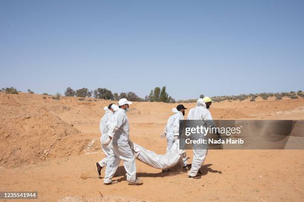 Members of the General Authority for Search and Identification of Missing Persons team carry one of the five bodies who was a victim of Al-Kaneyat...