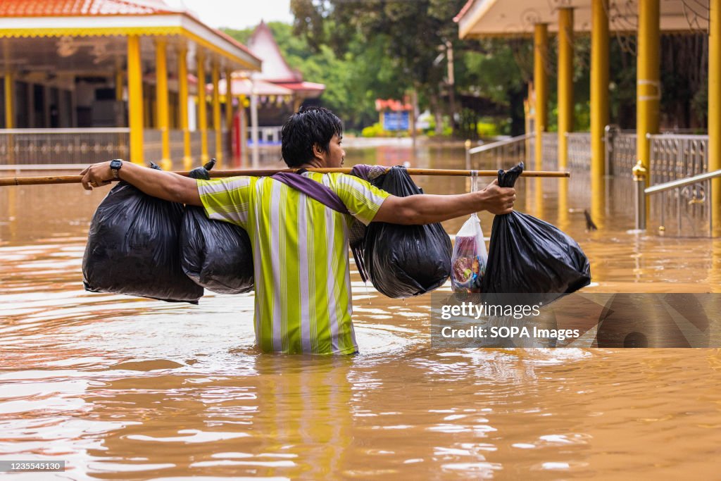 A man is seen walking on a submerged road.
Lopburi and many...