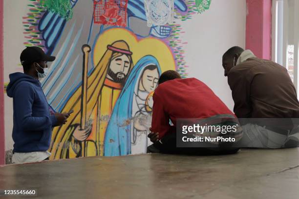 Haitian migrants in front of murals inside the Casa de Acogida Formación y Empoderamiento de la Mujer Migrante y Refugiada , located in Mexico City,...
