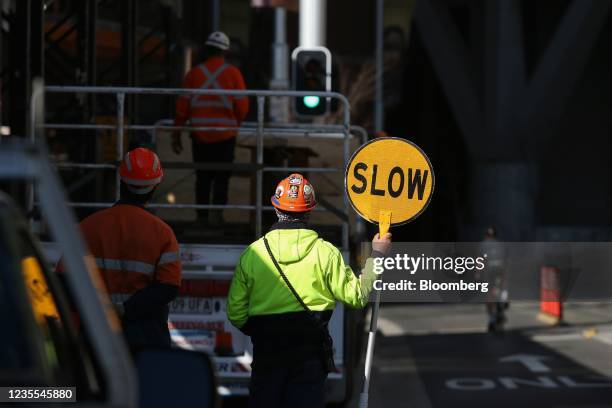 Construction worker holds a slow sign on a road outside a construction site in the central business district of Sydney, Australia, on Tuesday, Sept....