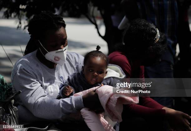 Haitian migrants sit on a bench outside the Mexican Commission for Refugee Support in Mexico City, where more migrants recently went to various...