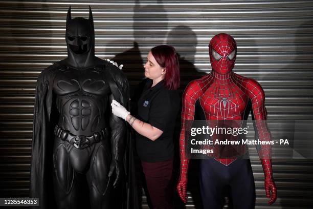 Prop Store employee adjusts Val Kilmer's Sonar Batsuit from 1995 film 'Batman Forever' next to Tobey Maguire's production made costume from 2007 film...