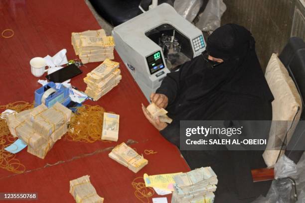 An employee counts stacks of Yemeni currency at the central bank in the southern port city of Aden on September 28, 2021. - Subject to the world's...