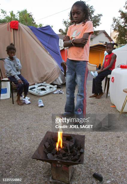 Assita Camara, neuf ans, se réchauffe près du feu avec ses soeurs Moui , six ans, et Kané, sept ans, à leur réveil, le 02 septembre 2005, avant de...