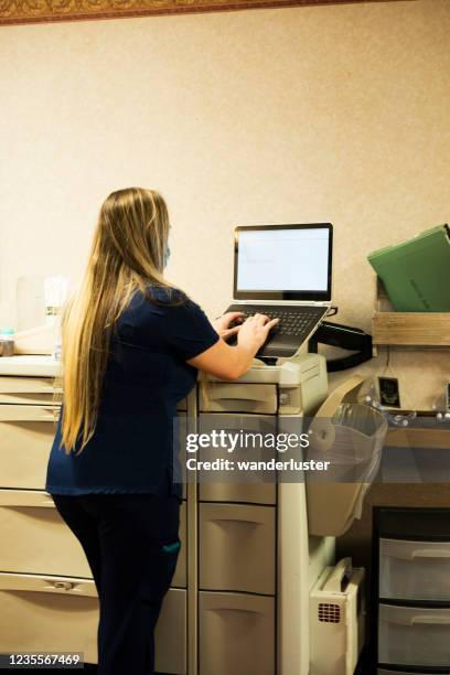 nurse charting into laptop - nurse charting computer stock pictures, royalty-free photos & images