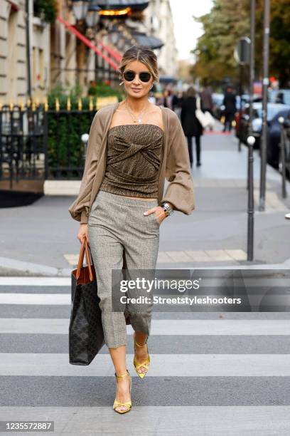 Influencer Gitta Banko wearing a low bubble ponytail hairstyle, a beige and gold scrunchie, a brown tube top with knot detail and logo print by...