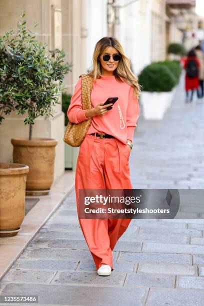 Influencer Gitta Banko wearing a salmon colored knitted pullover by t7berlin, salmon colored wide leg pants by Boscana, white sneaker by Saint...