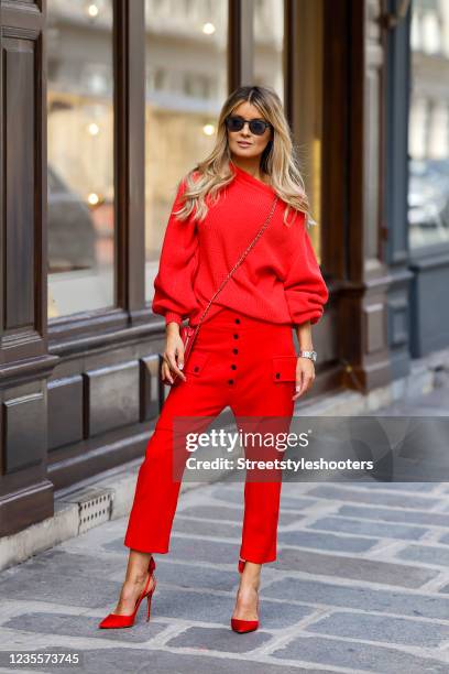 Influencer Gitta Banko wearing a red monochrome look with a red knitted sweater with puffy sleeves by t7berlin, red pants with large pockets, black...