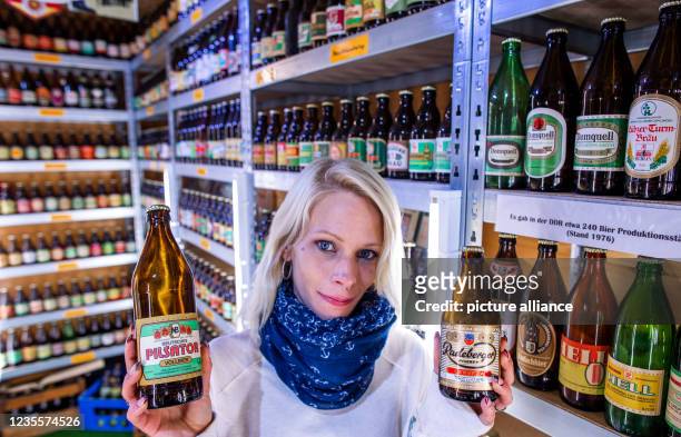 September 2021, Mecklenburg-Western Pomerania, Dabel: Museum operator Jessica Seidler shows two specimens from the collection of East German beer...