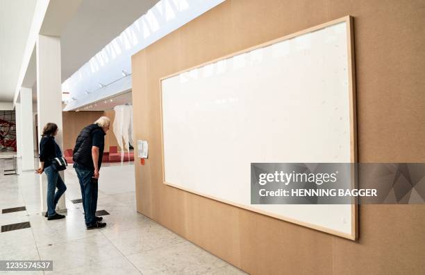 People stand in front of an empty frame hung up at the Kunsten Museum in Aalborg, Denmark, on September 28 2021. - The Danish museum loaned an artist...