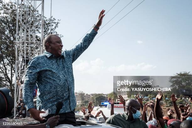 Kenya's President Uhuru Kenyatta waves to people after attending an inauguration of Kibra Level 3 hospital in Kibera slum in Nairobi on September 29,...