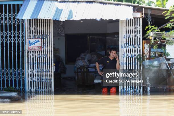 Man uses his mobile phone in a flooded house as Pasak Jolasid Dam overflows.According to the Royal Irrigation Department , tropical storm Dianmu and...