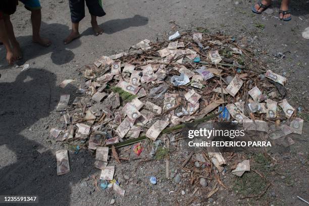 View of a pile of rubish with unused Venezuelan bolivar bills on a street of Puerto Concha town, Zulia state, Venezuela, on September 8, 2021. -...