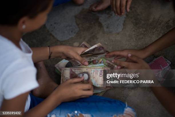 Children play cards and bet with unused Venezuelan bolivar bills on a street of Puerto Concha town, Zulia state, Venezuela, on September 9, 2021. -...