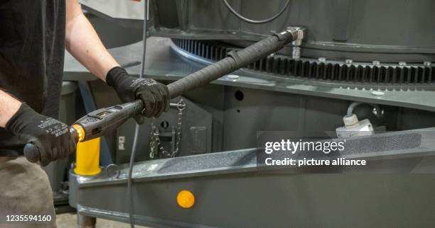 September 2021, Baden-Wuerttemberg, Biberach an der Riß: An employee uses a torque wrench to fit bolts to the slewing ring of a crane at the machine...