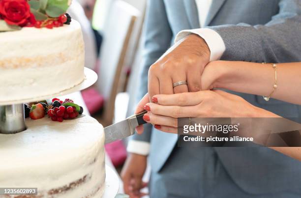 August 2021, Baden-Wuerttemberg, Elzach: A bride and groom cut the wedding cake during the wedding reception. Photo: Silas Stein/dpa