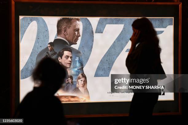 Woman walks past a poster of the latest James Bond movie No Time to Die at a PVR cinema in New Delhi on September 30, 2021.