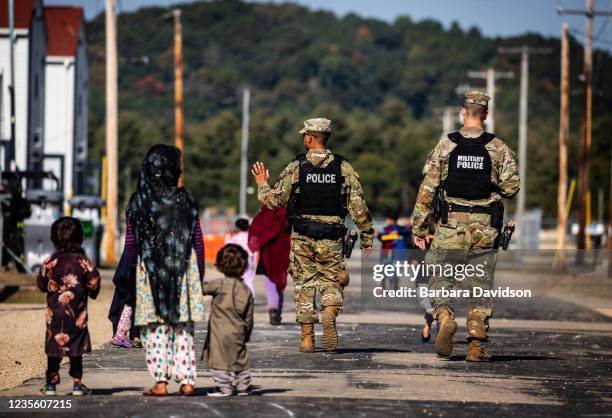 Military Police walk past Afghan refugees at the Village at the Ft. McCoy U.S. Army base on September 30, 2021 in Ft. McCoy, Wisconsin. The Village...