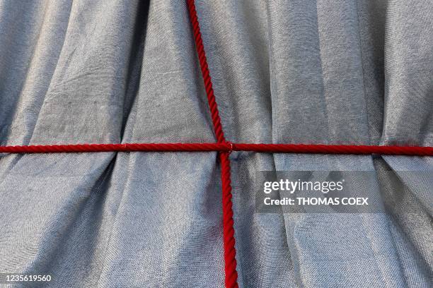 This photograph shows the silver-blue fabric and red ropes wrapped around the Arc de Triomphe, as designed by the late artist Christo, as part of the...