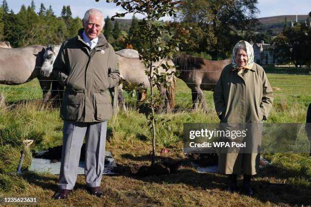 Queen Elizabeth II and Prince Charles, Prince of Wales pose after planting a tree at the Balmoral Cricket Pavilion, to mark the start of the official...