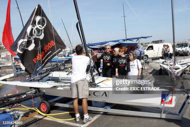 Un participant à la semaine olympique de voile attache une banderole au mât de son voilier devant des membres du collectif de Reporters Sans...