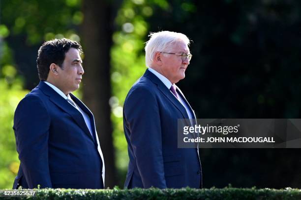 German President Frank-Walter Steinmeier and Libya's President Mohammad Younes Menfi stand as they listen to the national anthems during their...