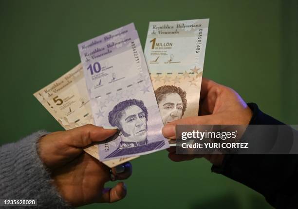 People show the new five and ten bolivar bank notes put in circulation by the Central Bank of Venezuela as part of the currency reconversion, and...