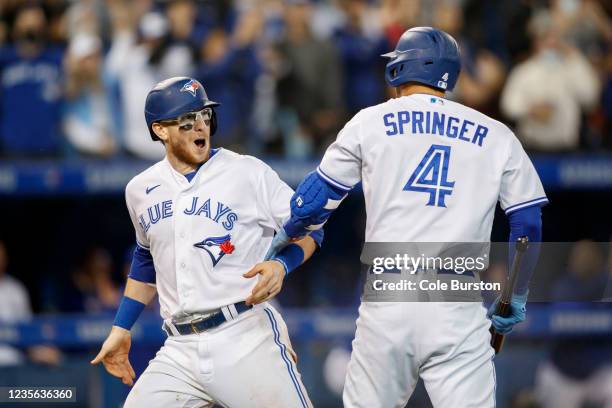 Danny Jansen and George Springer of the Toronto Blue Jays celebrate Jansens run off a Cavan Biggio double in the sixth inning of their MLB game...