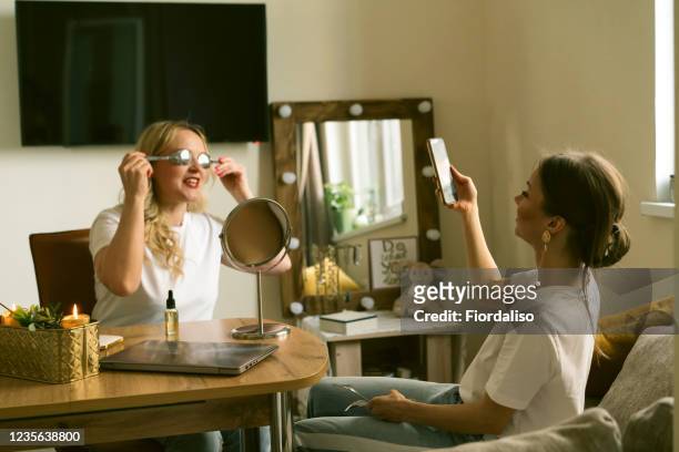 two beautiful girlfriend doing facial massage with spoons and laughing - content stock pictures, royalty-free photos & images