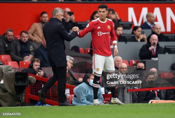 Manchester United's Norwegian manager Ole Gunnar Solskjaer shakes hands with Manchester United's Portuguese striker Cristiano Ronaldo as he comes off...