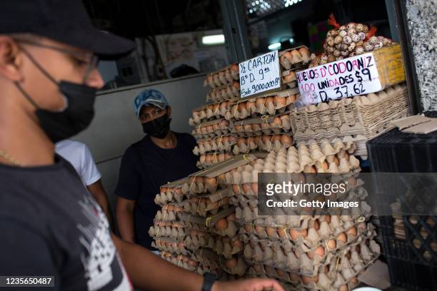 Workers at a food shop wait for customers as items' prices are written in old and new Bolivar currencies at a public market on October 2, 2021 in...