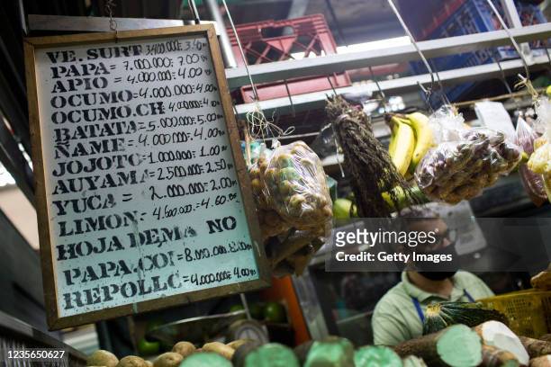List of prices at a fruit and vegetables shop are written in in old and new Bolivar currencies at a public market on October 2, 2021 in Caracas,...