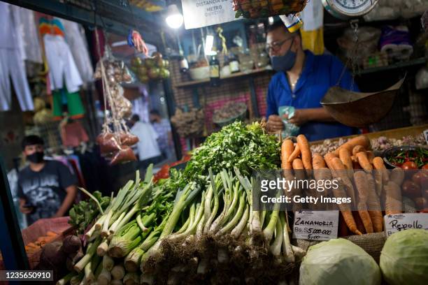 Worker places papers showing item's prices in both old and new Bolivar currencies at a public market on October 2, 2021 in Caracas, Venezuela....